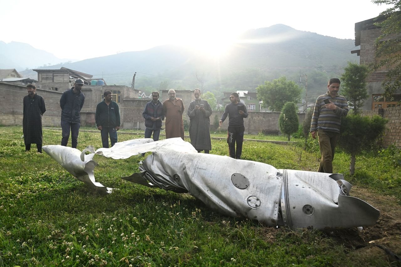 People look at the debris of an aircraft in Wuyan, India-administered Kashmir, on Wednesday. CNN cannot independently verify who the aircraft belonged to or what brought it down.