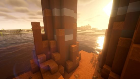 minecraft-shaders-bsl Minecraft shaders - the sun sets through the buttes of a badlands biomes, over realistic looking water, with BSL shaders installed